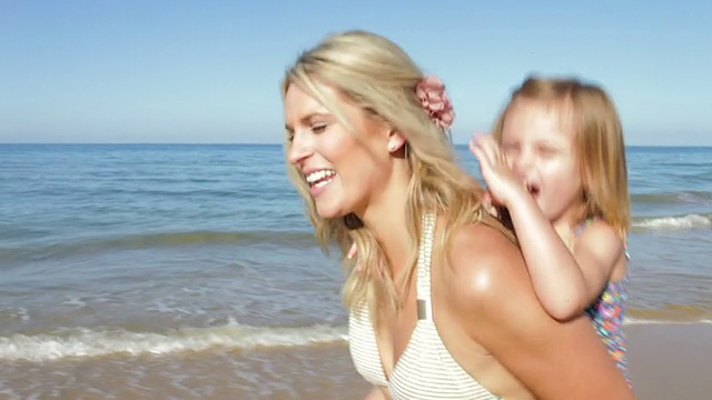 妈妈在沙滩上背着女儿视频素材