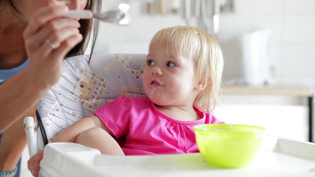 母亲在高椅上给女儿喂酸奶视频素材