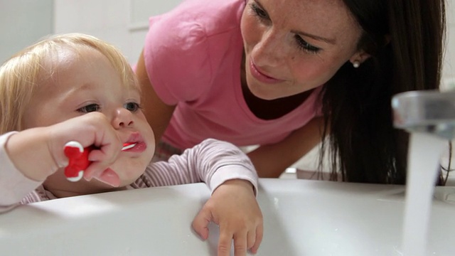 母亲帮助小女孩在浴室刷牙视频素材
