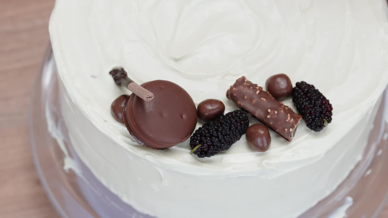 糕点师用圆形巧克力饼干装饰蛋糕的俯视图。视频下载