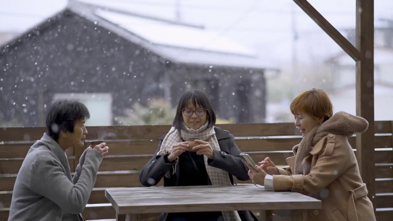 亚洲华人家庭在后院边喝热饮边下雪视频下载