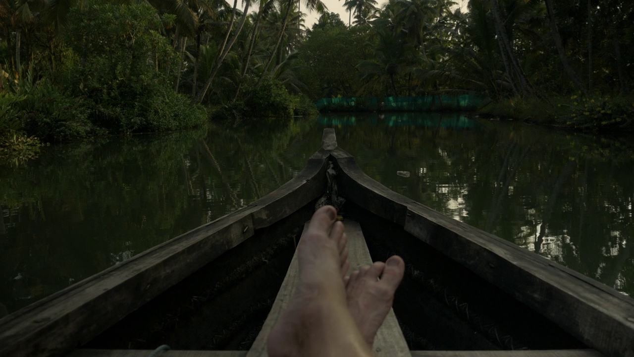 在门罗岛喀拉拉邦的丛林中，一名游客漂浮在一条河上的木船上，以第一人称视角观看。独木舟的视角。视频素材