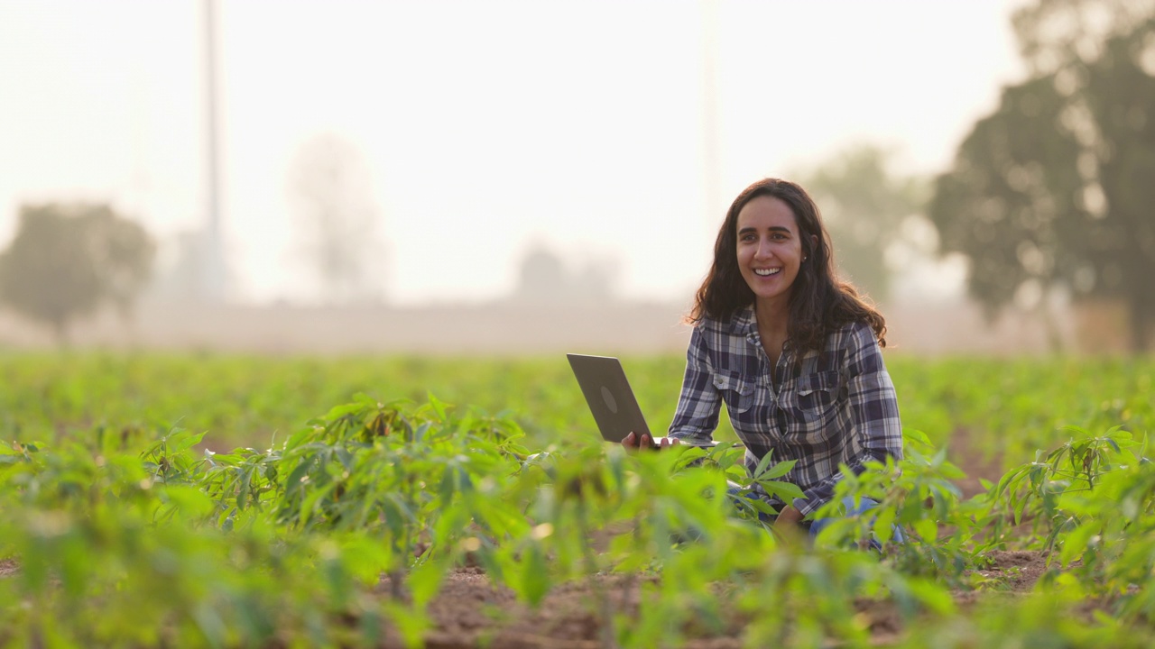 西班牙裔妇女农民手里拿着笔记本电脑研究可持续性和增长分析。农业、种植园和园艺概念视频下载