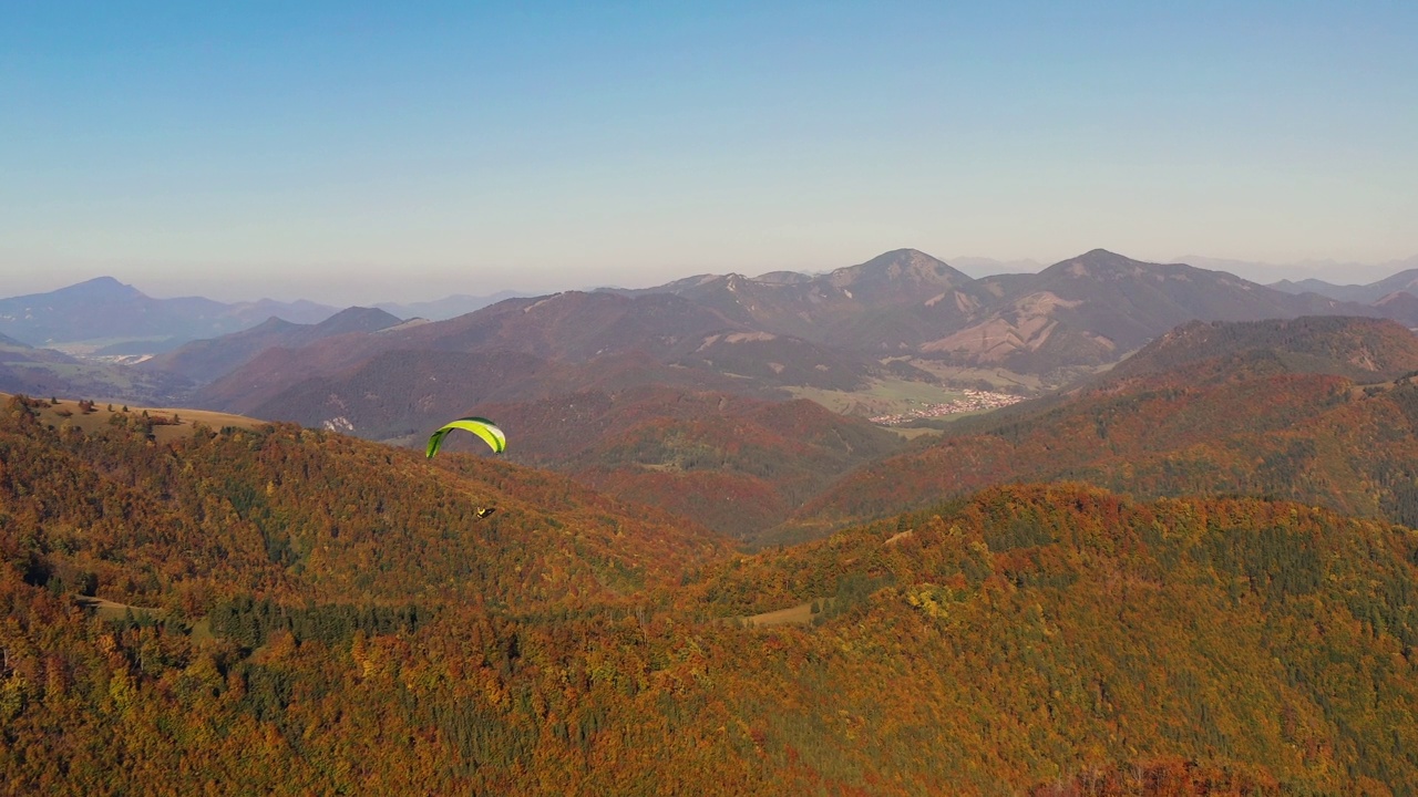 滑翔伞在蓝天中飞行，背景是山。视频素材