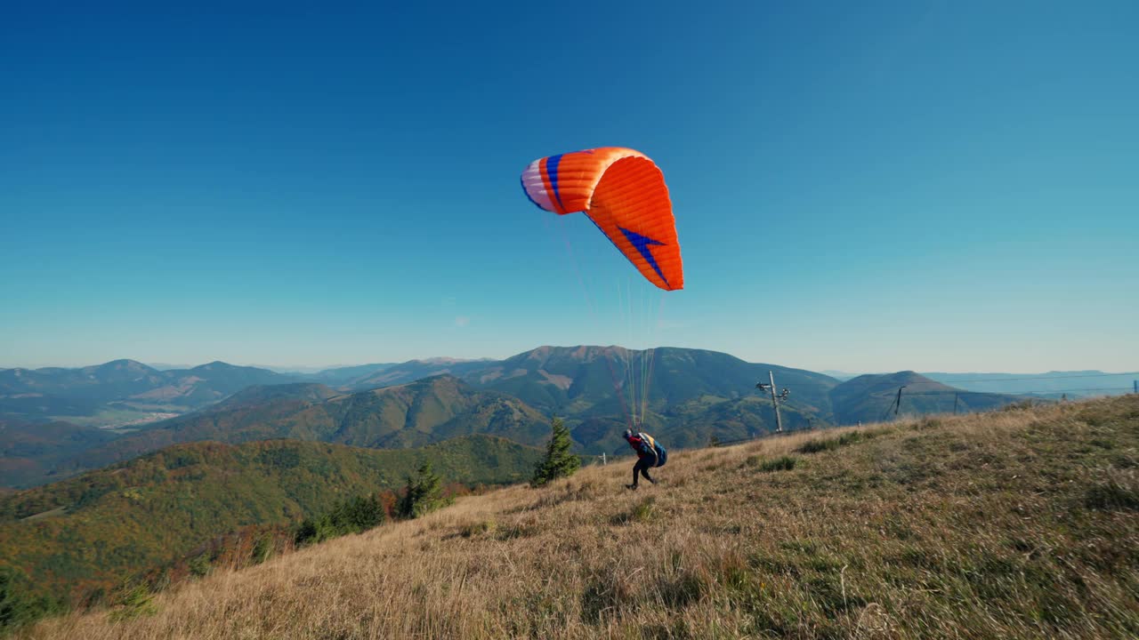 滑翔伞在蓝天中起飞，背景是山。视频素材