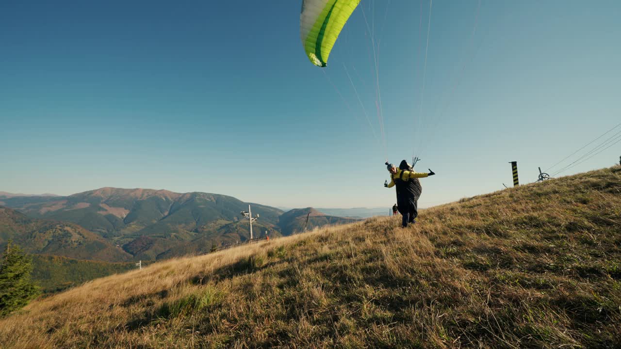滑翔伞在蓝天中起飞，背景是山。视频素材