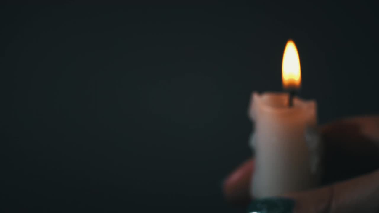 在黑暗的特写中，男人的手拿着蜡烛视频下载