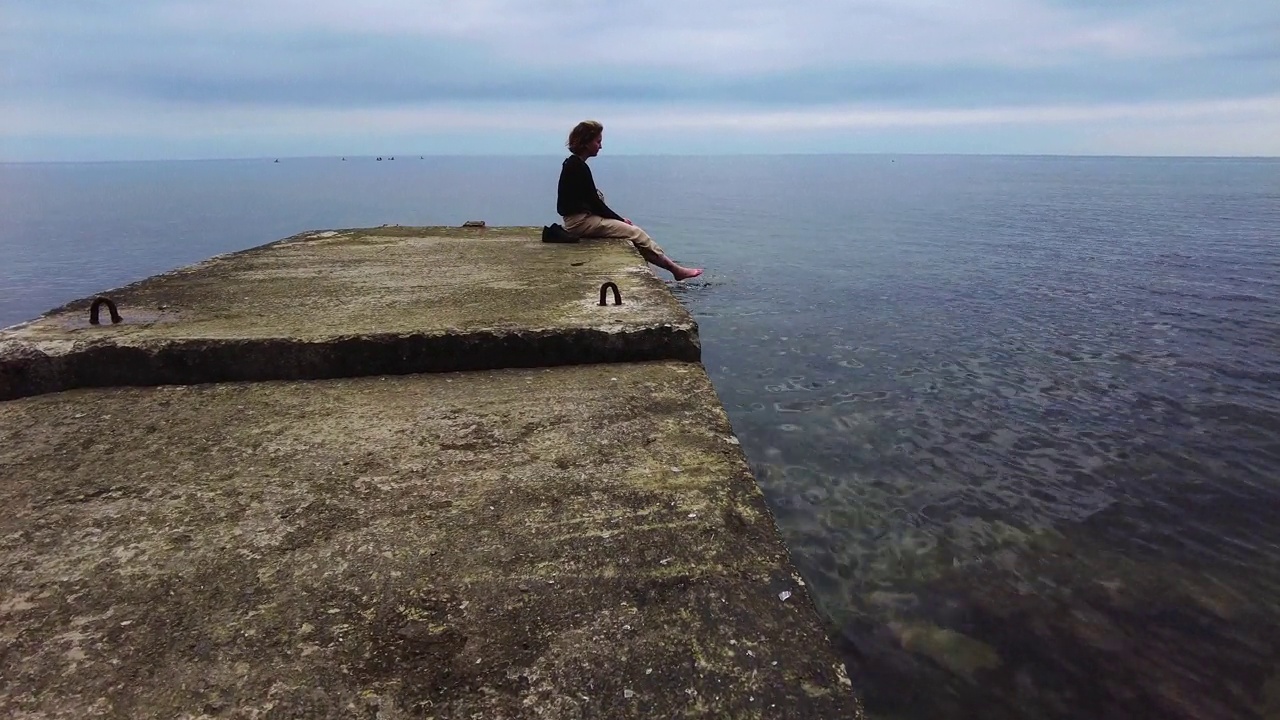 一个年轻的女孩正坐在黑海沿岸。视频下载