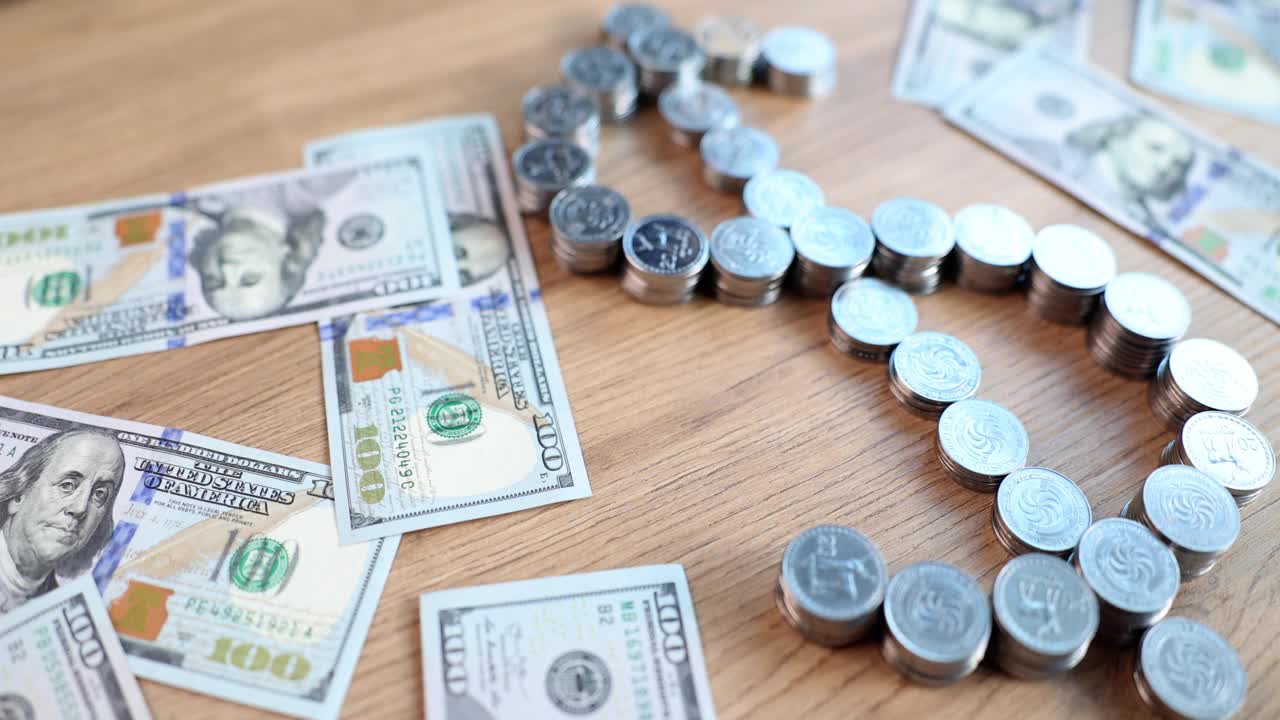 一美元钞票和一堆美元符号形状的硬币放在桌子上视频下载