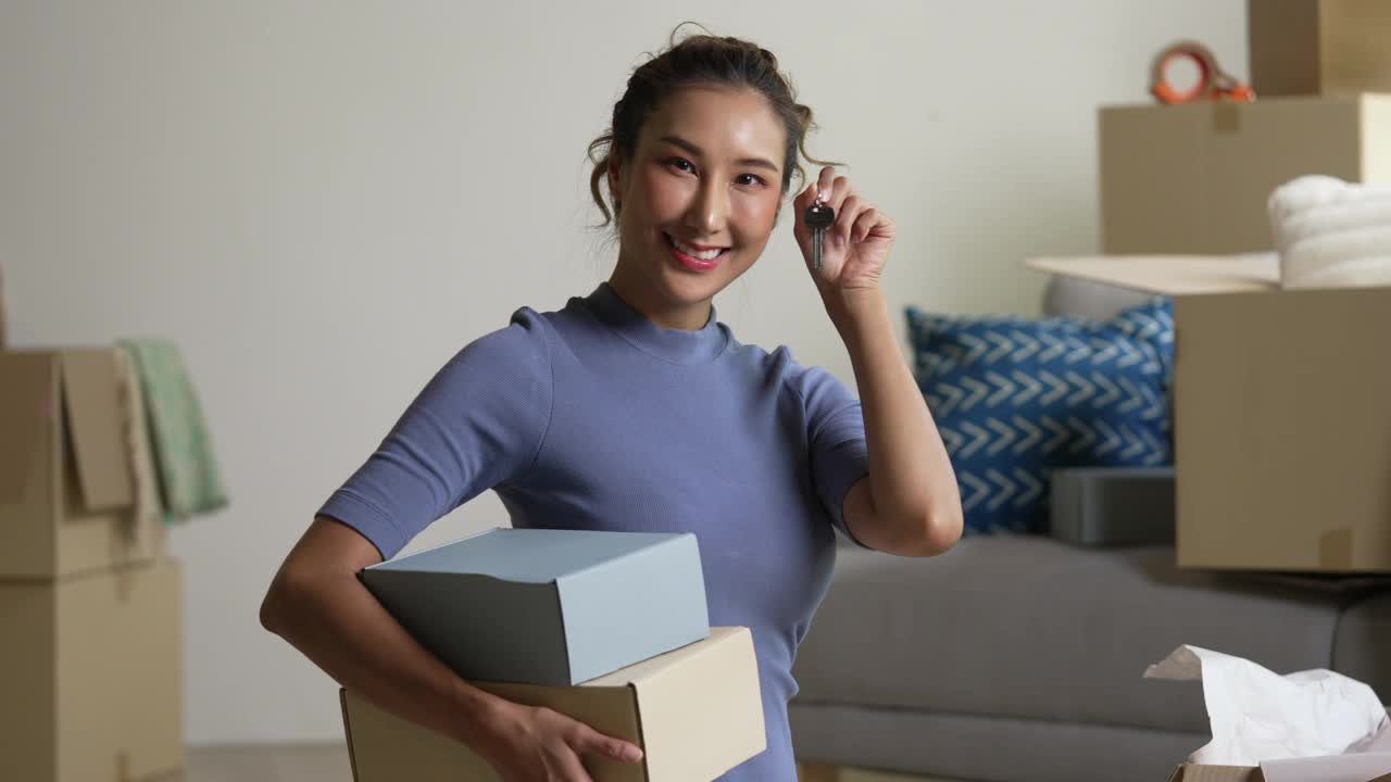 快乐的年轻亚洲女人展示新房子的钥匙。视频下载