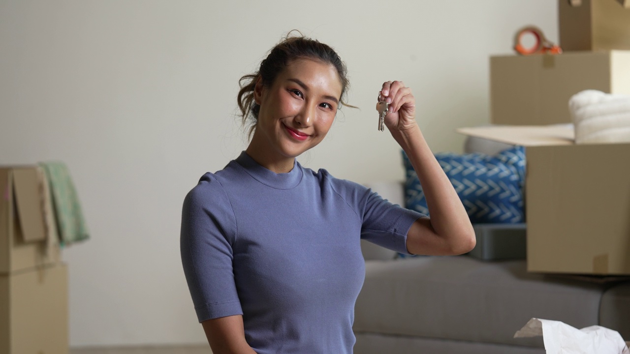 快乐的年轻亚洲女人展示新房子的钥匙。视频下载