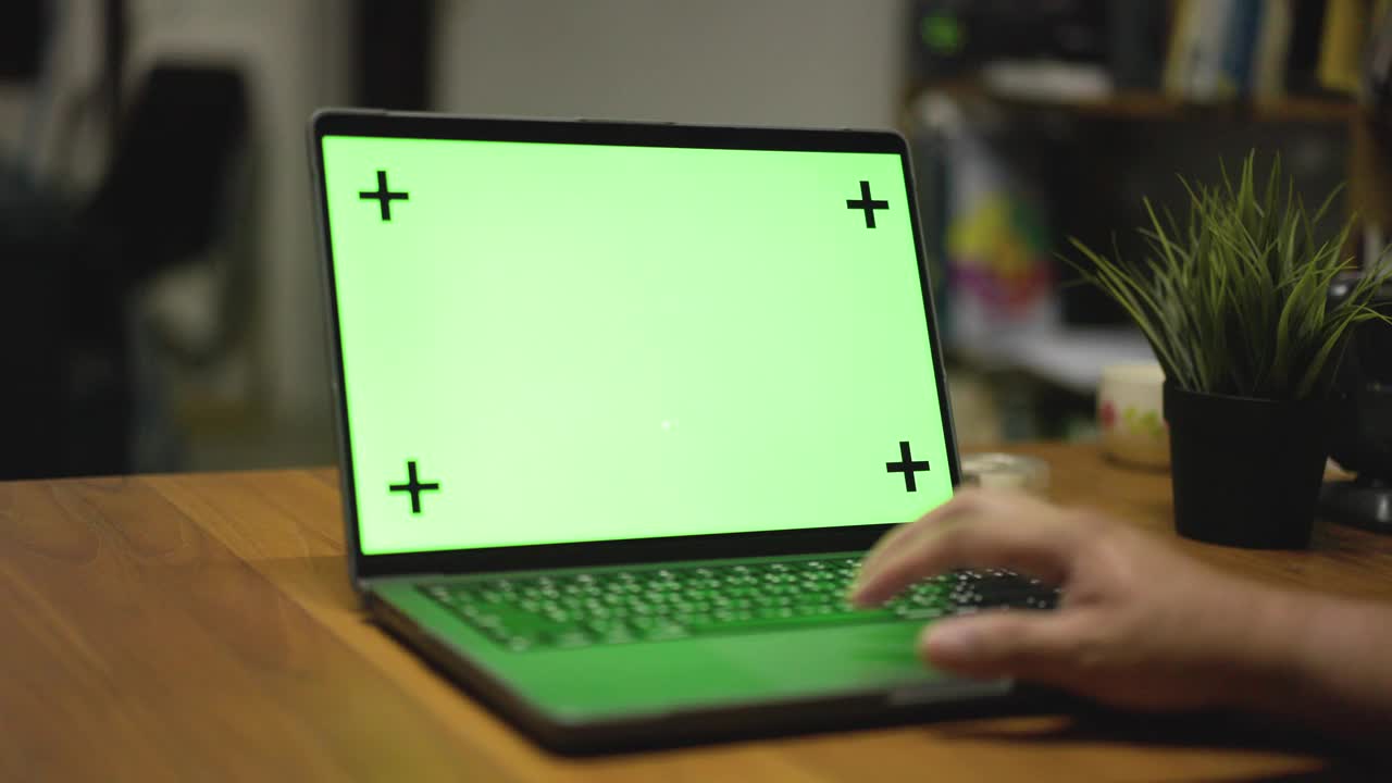 绿屏笔记本电脑，笔记本电脑站在家里的木桌上，晚上在家工作视频素材