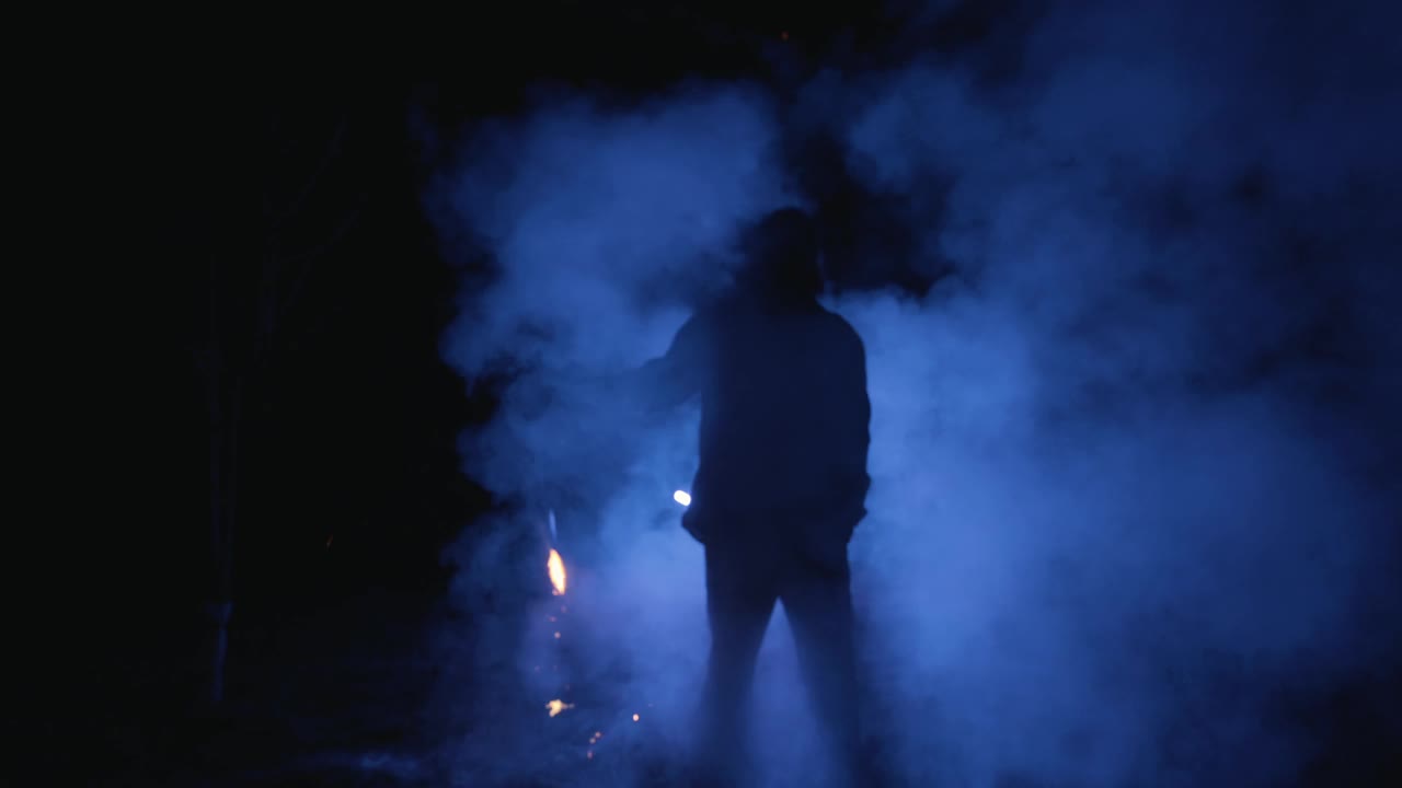 SLO MO男火焰艺术家在黑暗中旋转发光的火炬散发烟雾视频素材