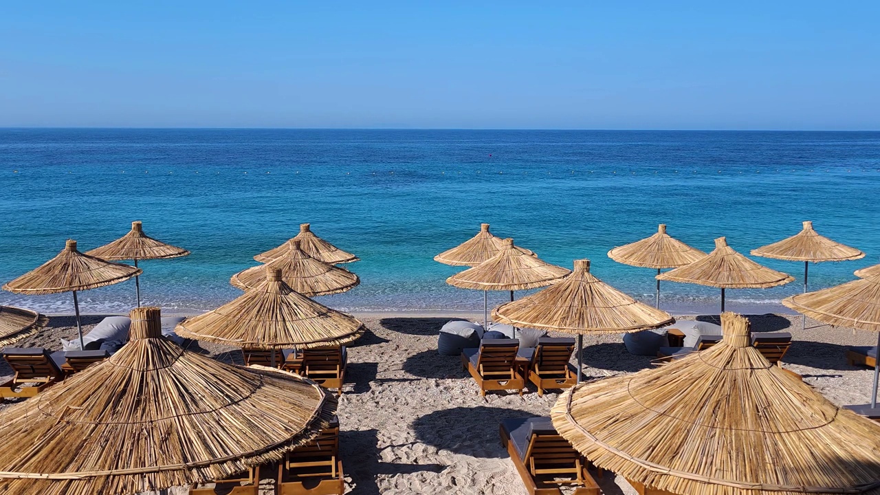 蔚蓝的绿松石海和晴朗的天空，在一个阳光明媚的暑假，在安静的沙滩上，有太阳椅和伞，阿尔巴尼亚爱奥尼亚海岸线视频素材