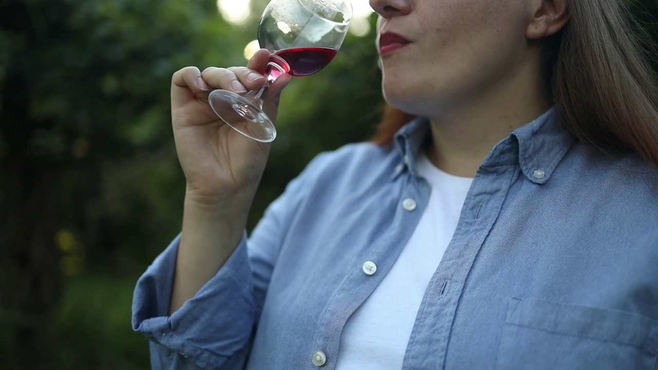 职业女性侍酒师在夕阳下的葡萄园里用葡萄酒杯品尝和嗅闻红酒视频素材