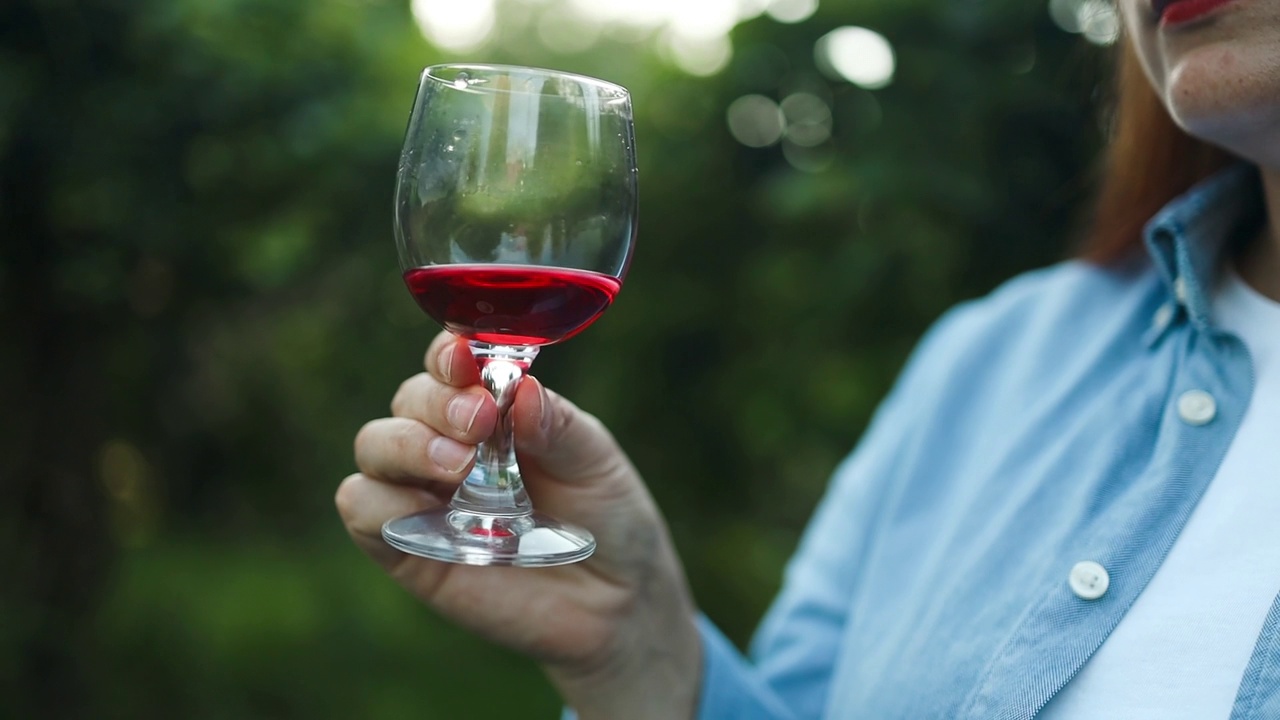 职业女性侍酒师在夕阳下的葡萄园里用葡萄酒杯品尝和嗅闻红酒视频素材