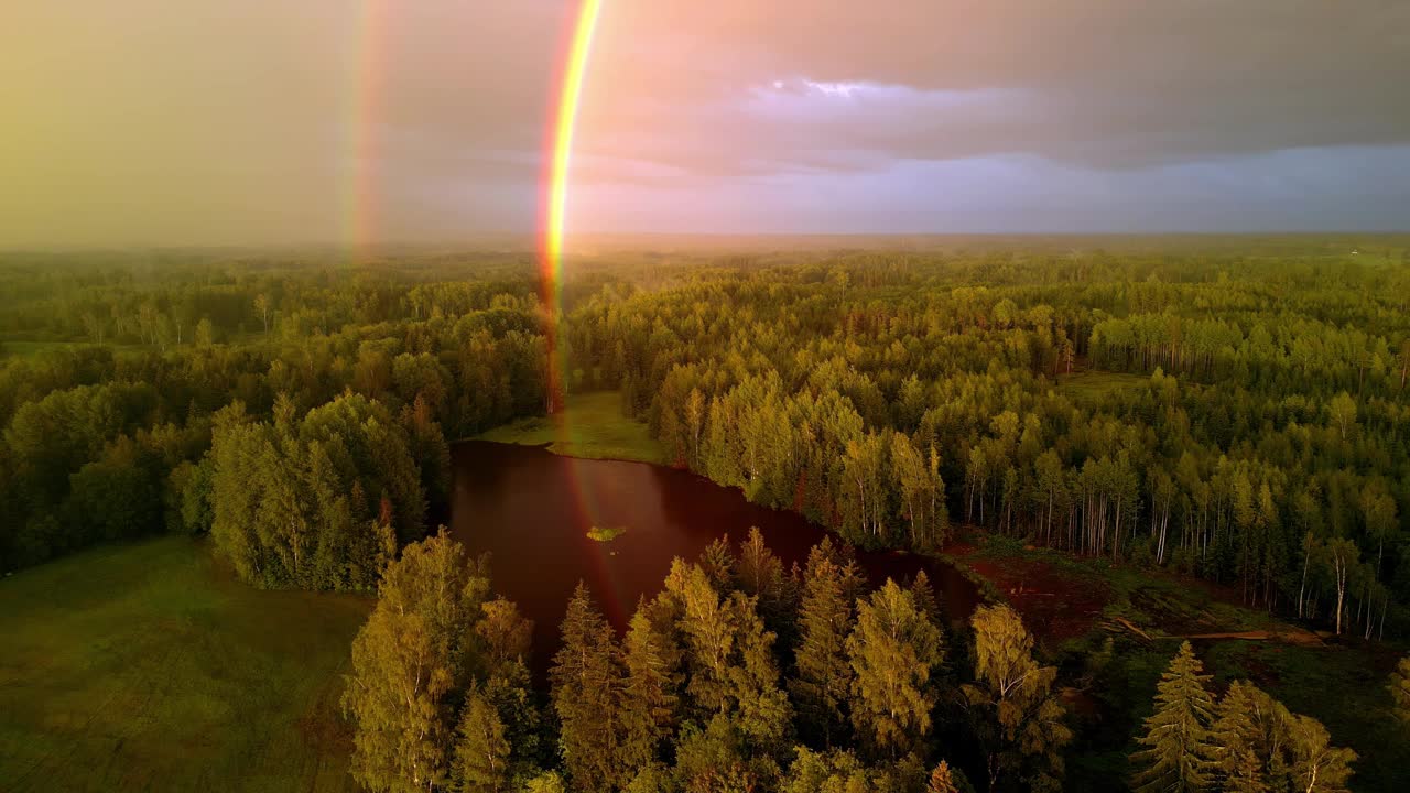 拉脱维亚风景秀丽的湖泊和森林上反射着五彩缤纷的光，这是一道美丽的双彩虹。空中无人机跟踪拍摄。视频下载