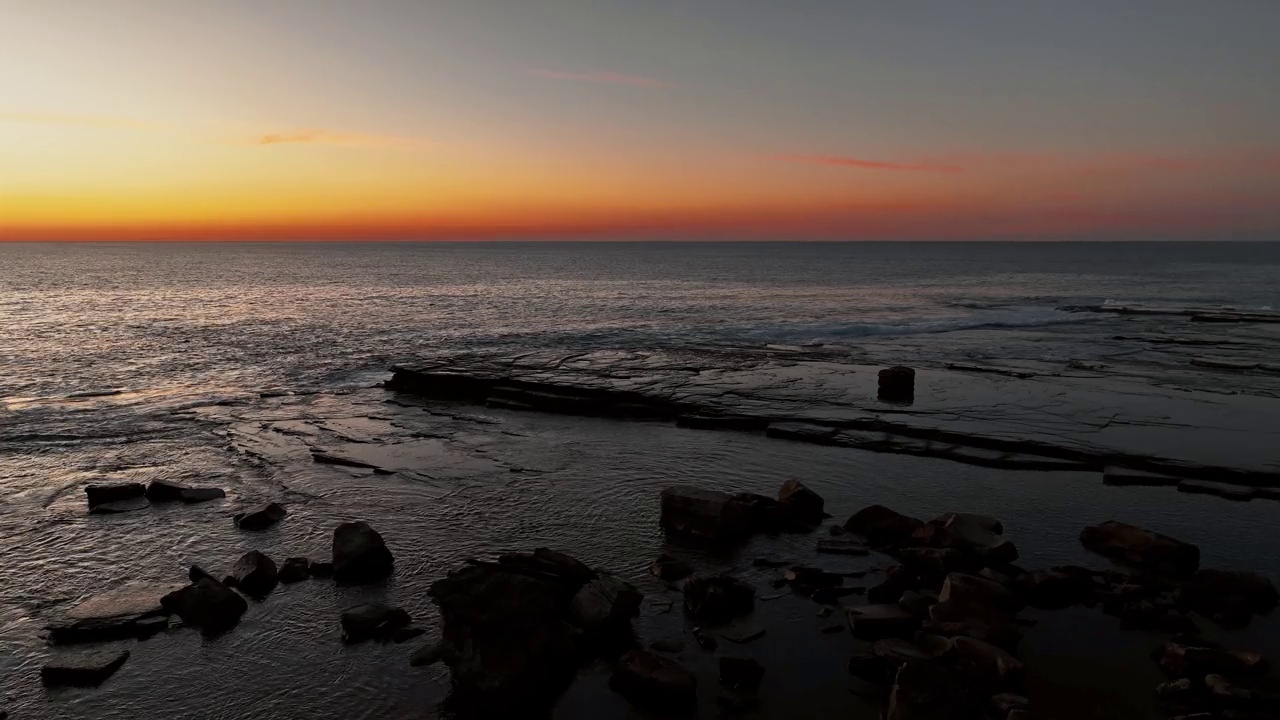 日出在平静的海面和多岩石的海湾视频下载