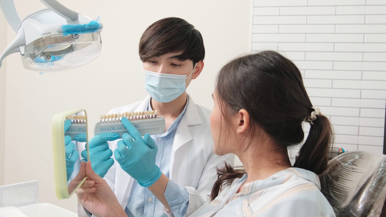 一名亚洲男牙医在牙科诊所向一名女病人讲解牙齿护理。视频下载