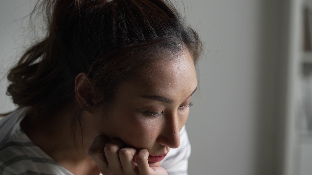 年轻的亚洲女性感到悲伤，疲倦和担心，在心理健康方面遭受抑郁症。视频下载