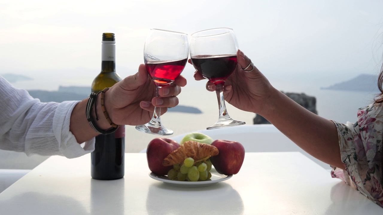 浪漫的情侣，用红酒杯干杯。全包度假村在圣托里尼希腊，浪漫的情侣水疗度假在天堂。品酒。视频下载
