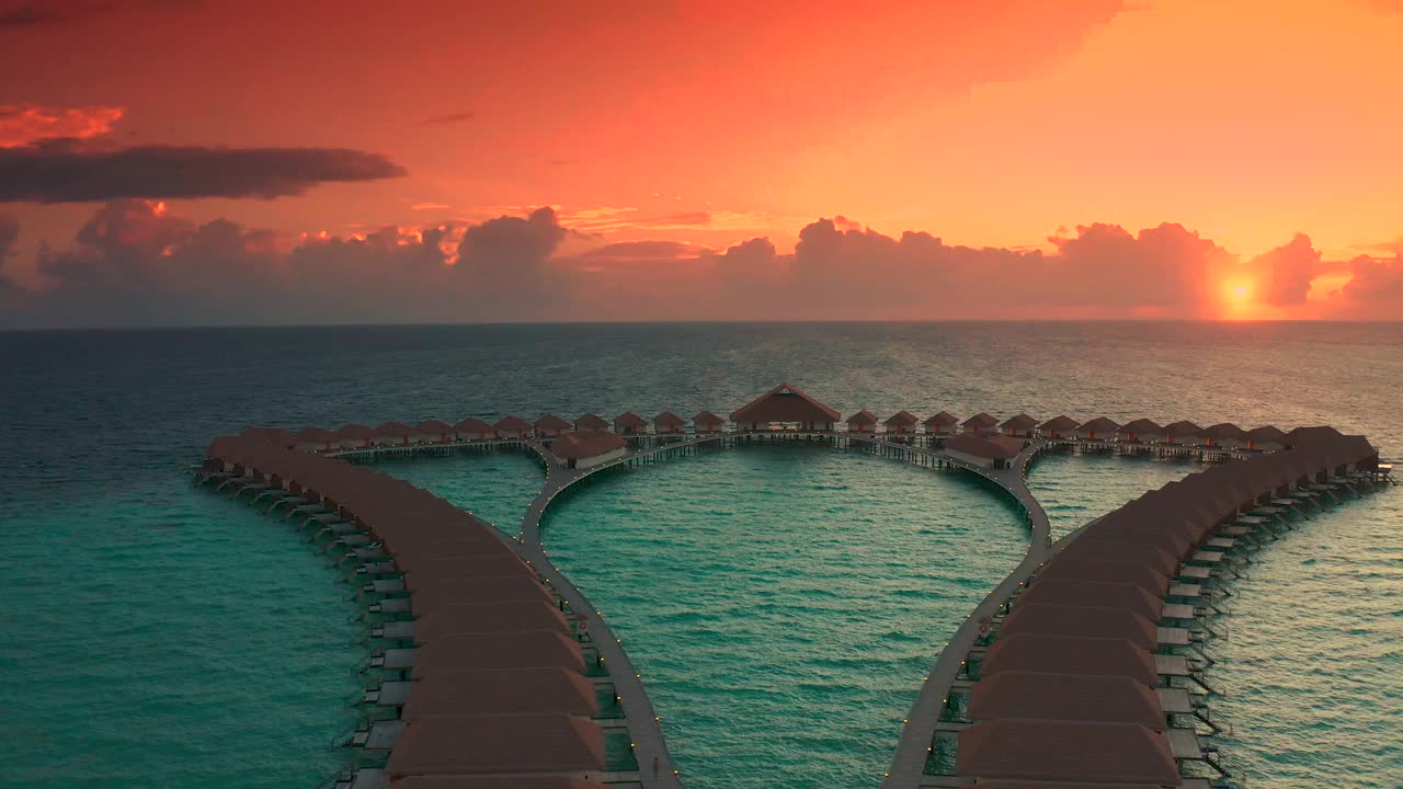 令人惊叹的全景日落马尔代夫。豪华度假别墅海景，彩色天空下柔和的led灯。美丽的黄昏天空和彩云。空中无人机观看4K。视频下载
