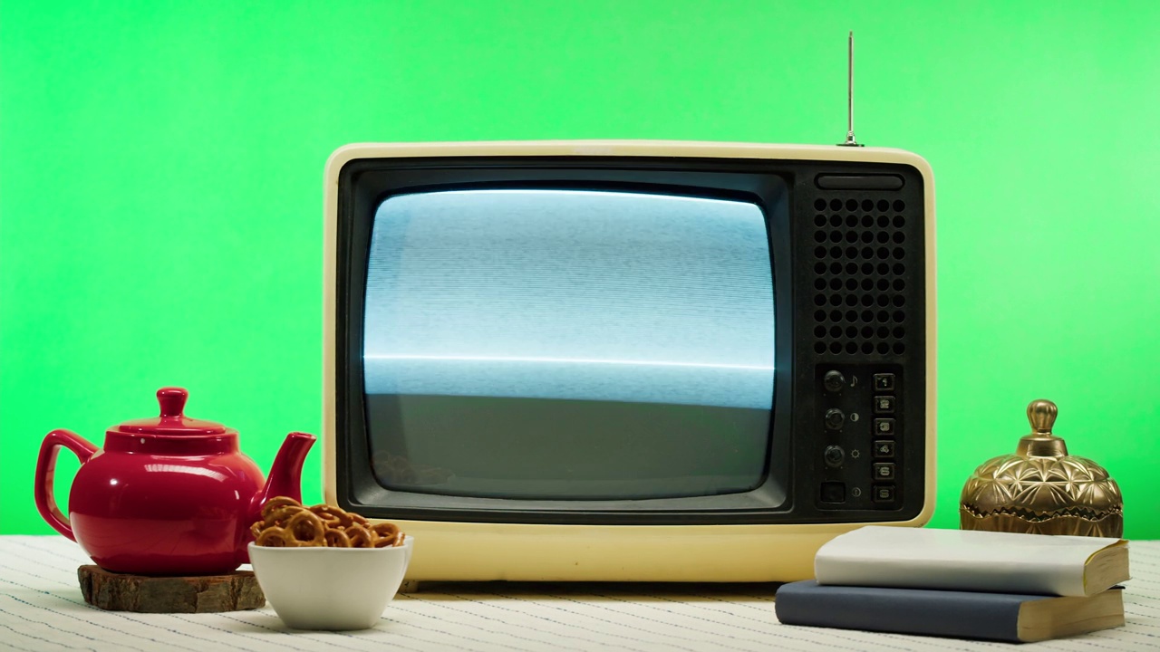 橙色背景的老式复古电视特写。带有灰色干扰屏幕和天线的坏电视，厨房桌子上的红色茶壶，信号接收不良，摄影概念。视频下载