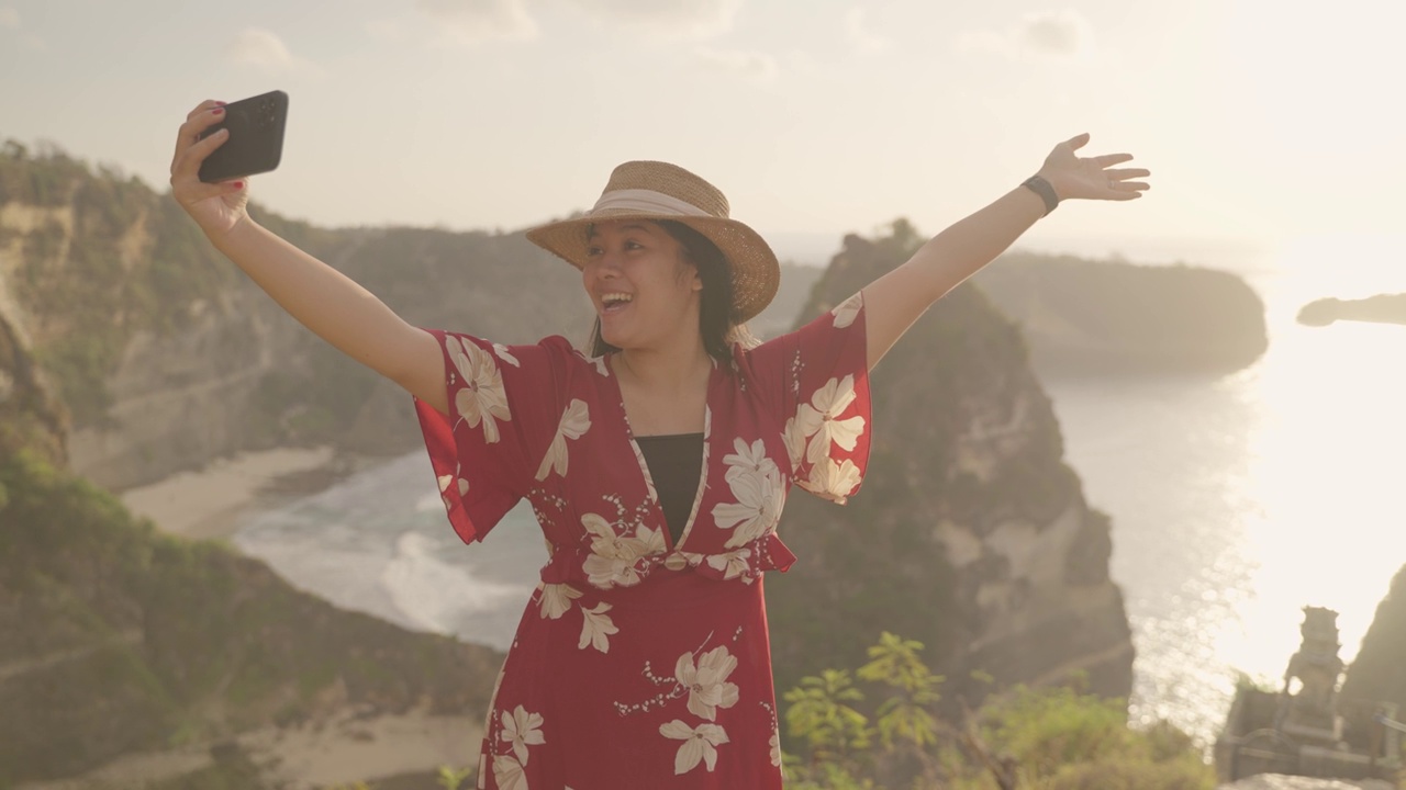 年轻的女游客在日出时在努沙佩尼达岛的阿屯海滩与大自然拍照的4K视频。印尼巴厘岛的热门旅游目的地。视频素材