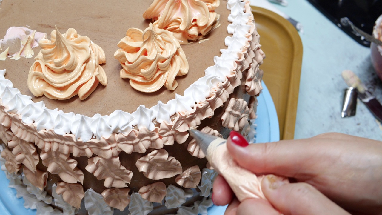 糖果女正在用酥皮袋把奶油倒在海绵蛋糕上，特写。糕点师正在做自制蛋糕。烹饪，烘焙和烹饪，家庭烹饪视频下载