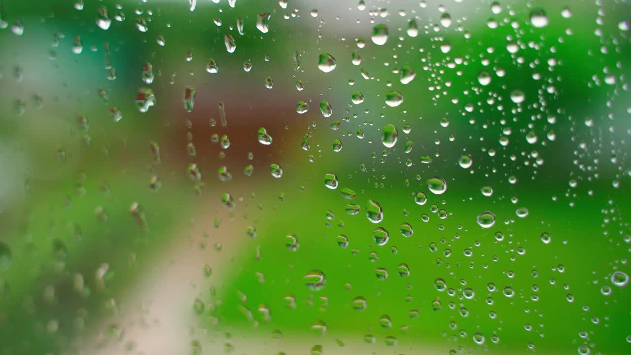 在模糊的背景上，雨滴从窗户上流下来视频素材