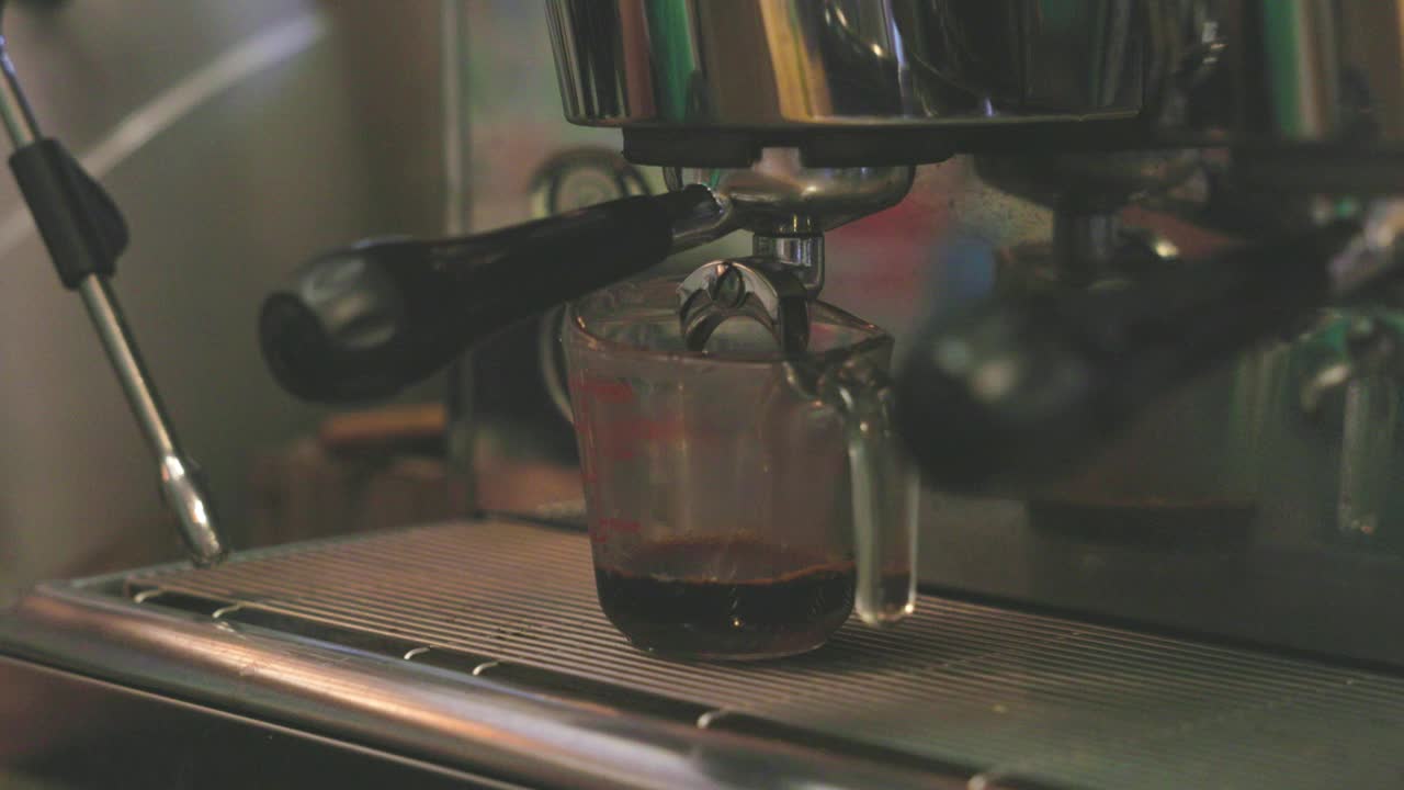 咖啡液从咖啡机的咖啡分配器中倒出来。咖啡机正在煮咖啡。视频下载