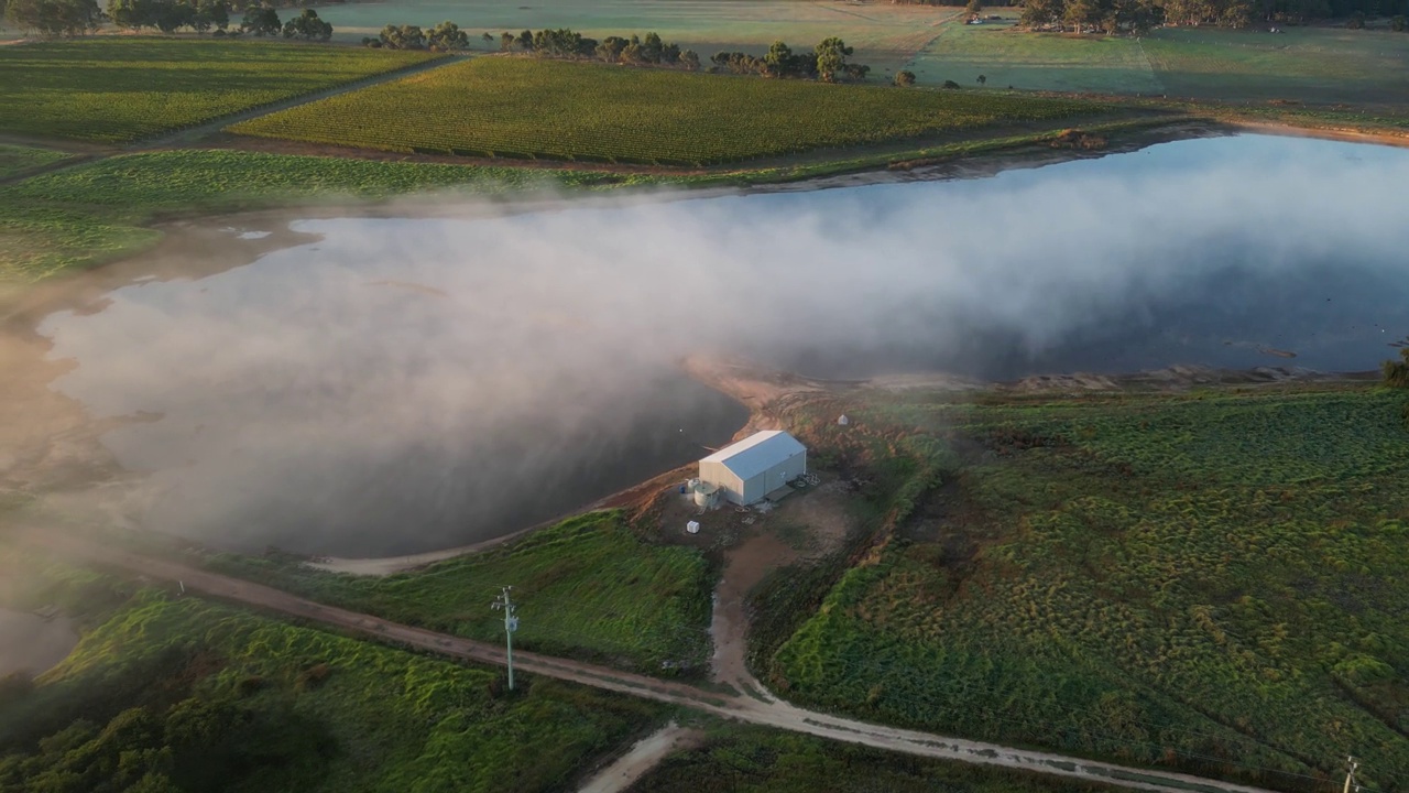 清晨日出时，神秘的雾笼罩着澳大利亚的乡村、农田和湖泊。，无人机轨道拍摄视频素材
