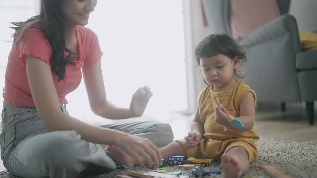 亚洲妈妈和小女孩在客厅里学习玩五颜六色的木制玩具视频下载