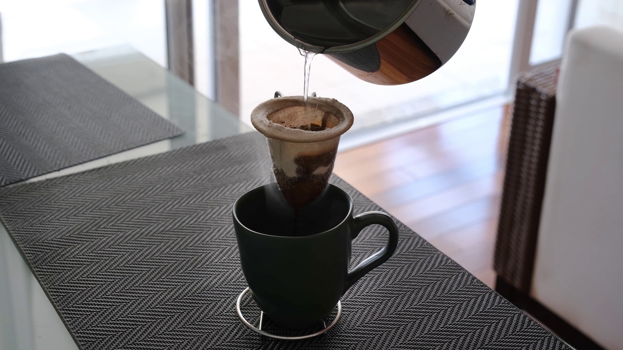 布制咖啡过滤器的特写，从金属水瓶中接收热水。视频下载