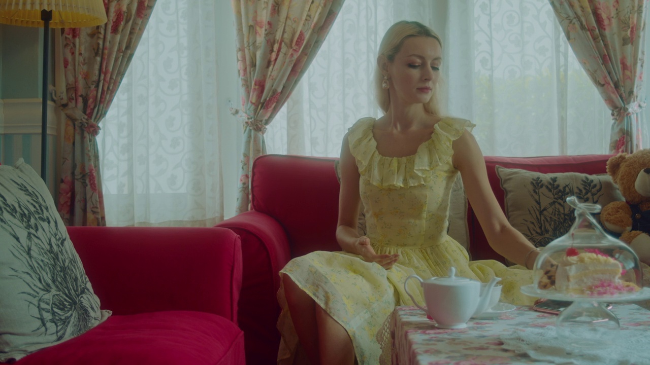 年轻的金发女郎穿着复古的裙子在喝茶视频下载