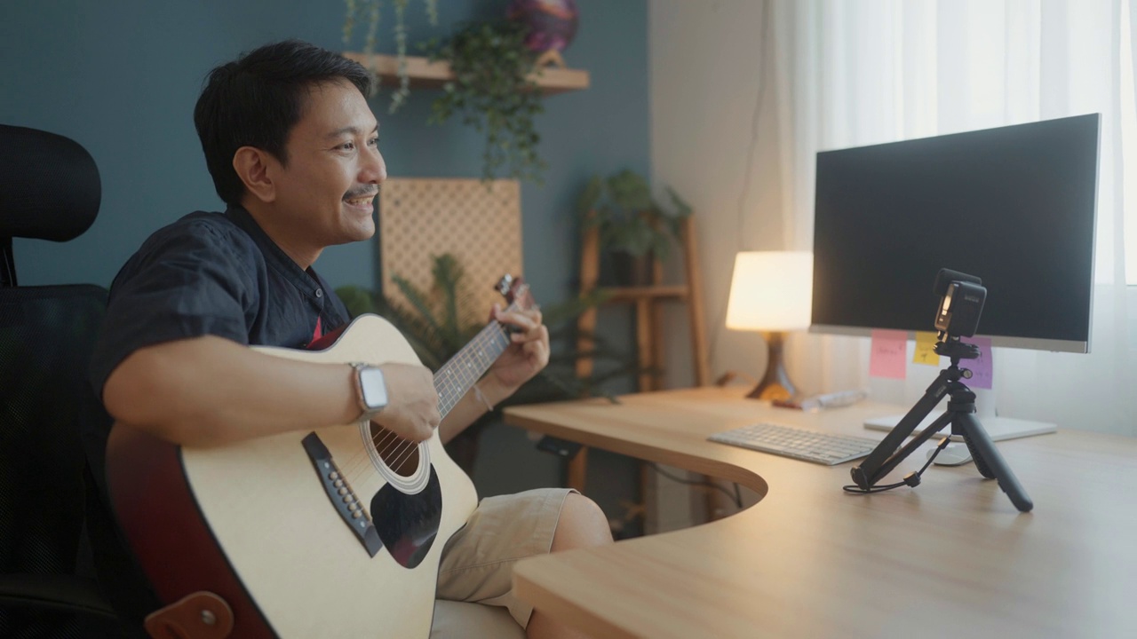 亚洲老人一边听不同风格的音乐，一边学习弹吉他。视频素材