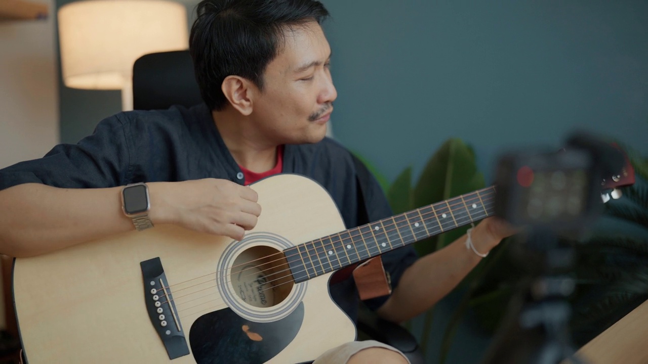 有吸引力的亚洲男子youtube直播表演弹吉他和唱歌。视频下载