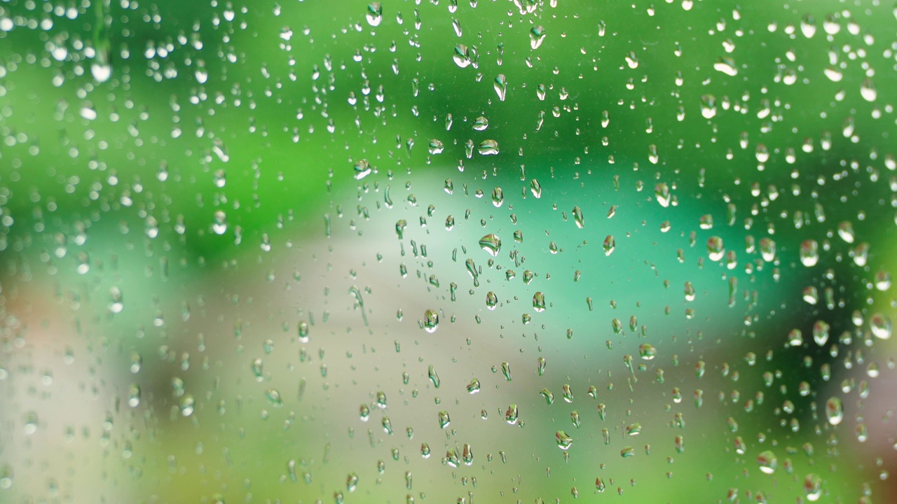 雨滴滴落在窗户上，在模糊的背景上流下特写视频素材
