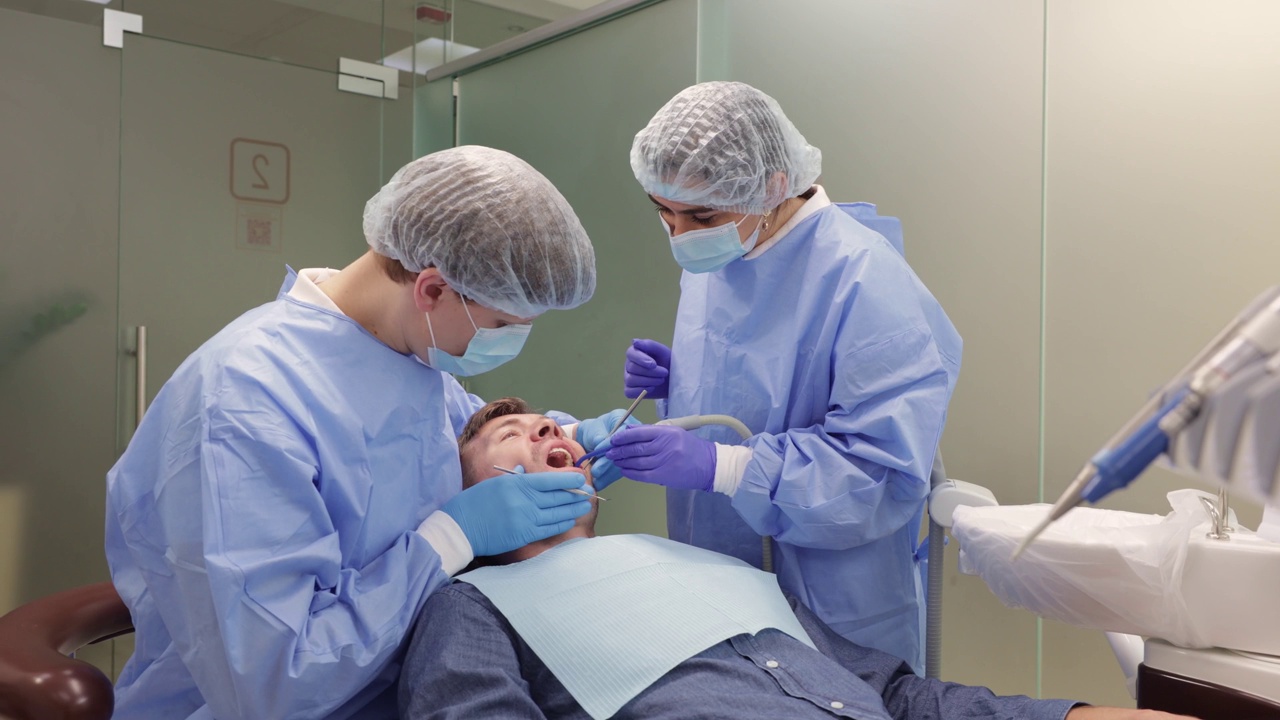 牙科医生和助手在牙科诊所用牙镜检查病人的牙齿视频下载