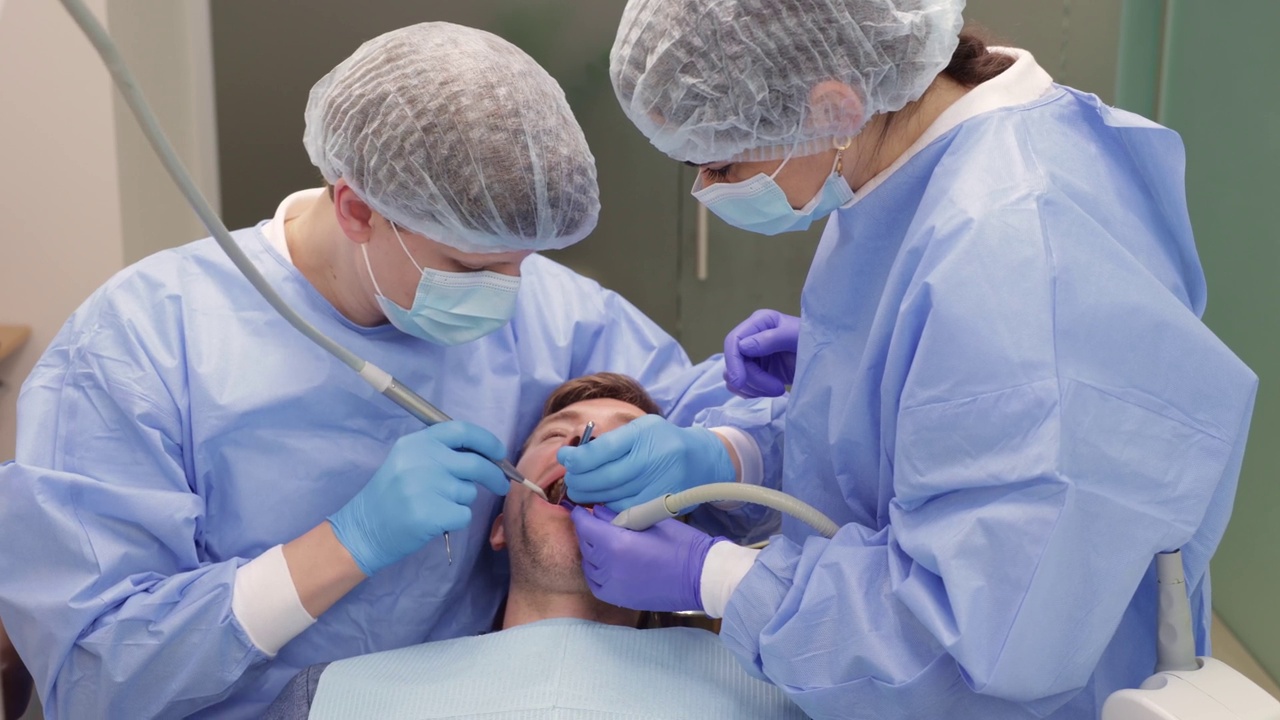 牙科医生和助手在诊所为病人封堵裂缝。视频下载