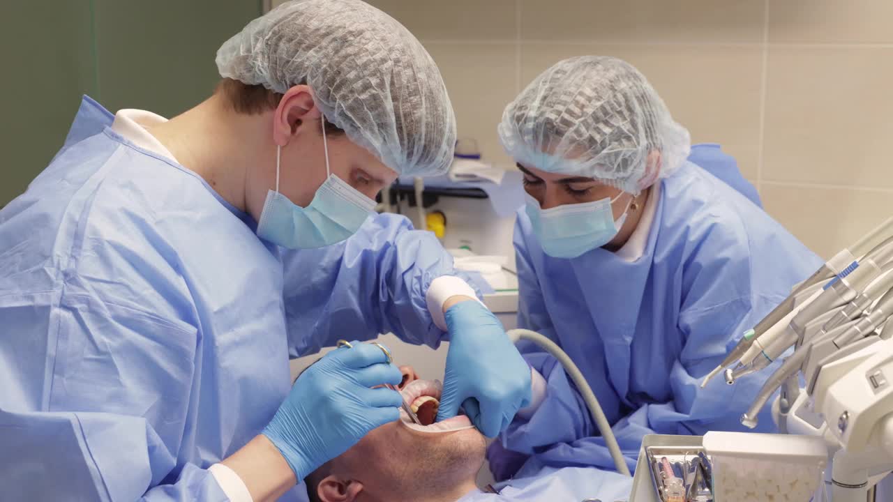 牙医和助手正在缝合病人的牙龈视频下载