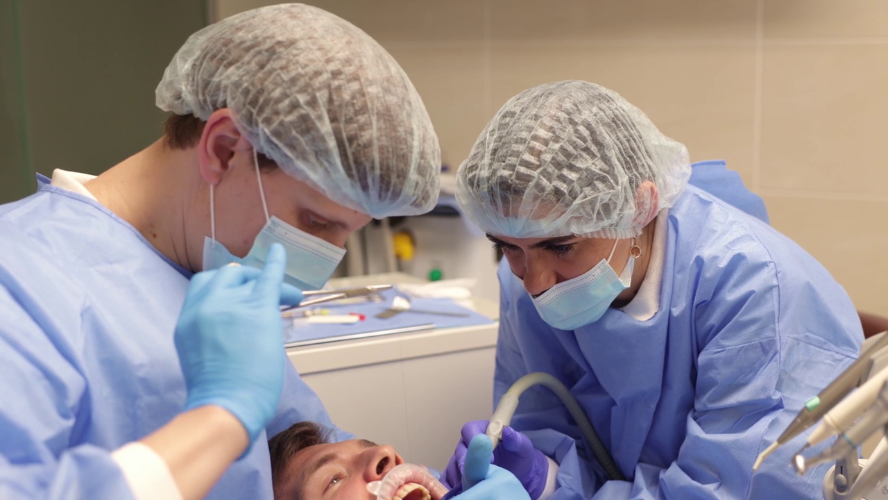 牙医和助手正在缝合病人的牙龈视频下载