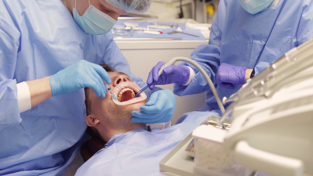 牙科医生在牙科治疗前给男性病人注射麻醉剂。视频下载