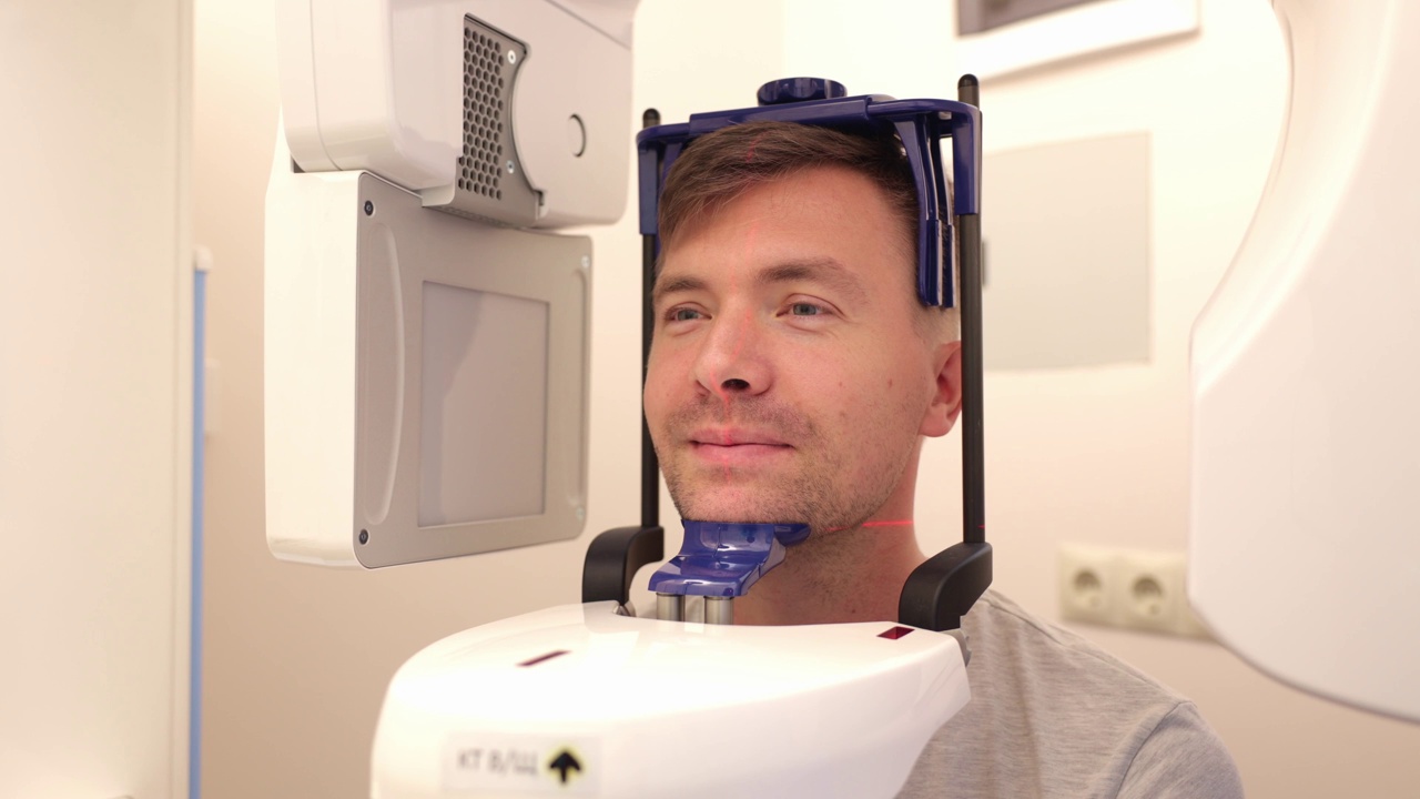 装有头颅测量孔的牙科x光机，一名男子正在拍摄自己的脸部照片。视频下载