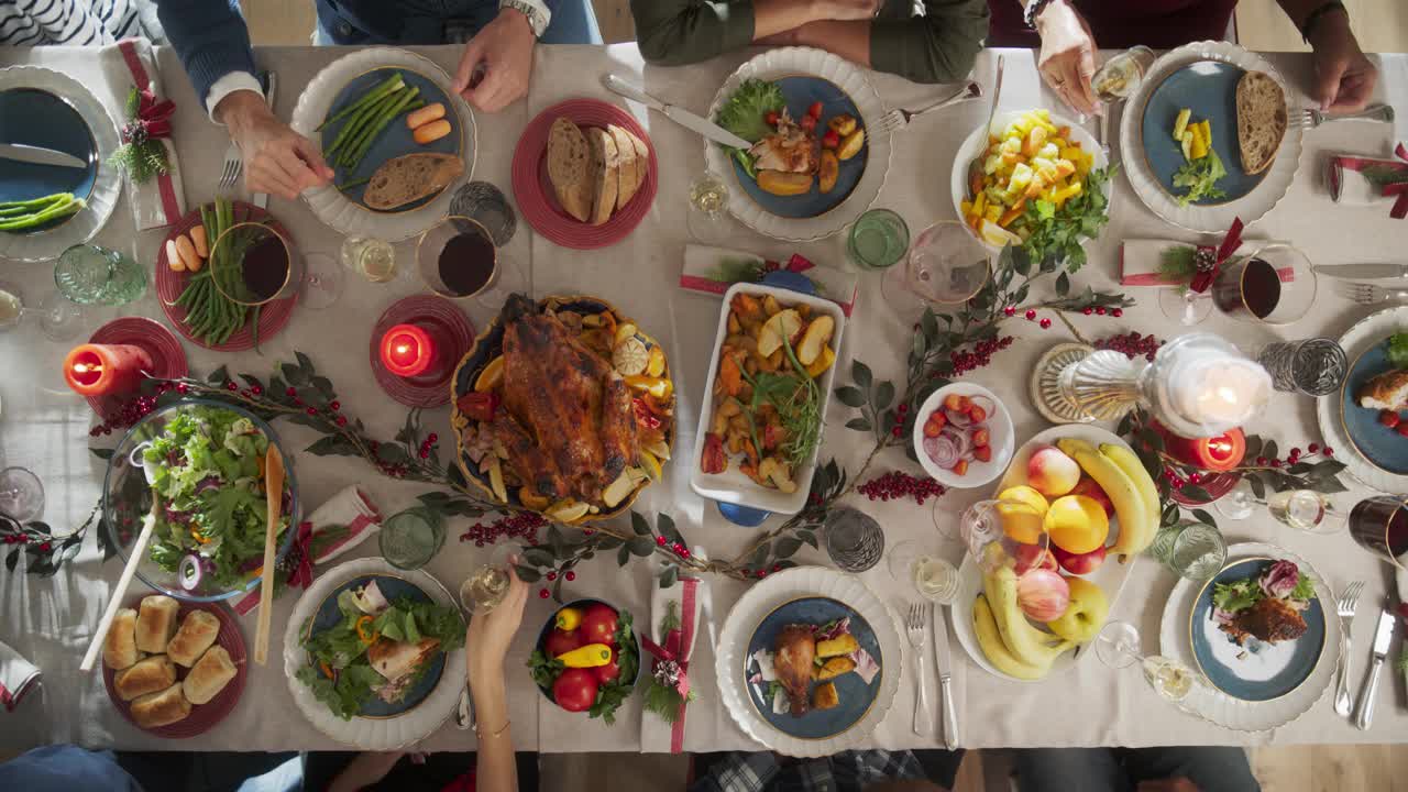 家人和朋友聚在家里吃传统的圣诞晚餐，烤火鸡盛宴。从上往下看，人们举起香槟酒杯举杯，一起庆祝节日视频下载