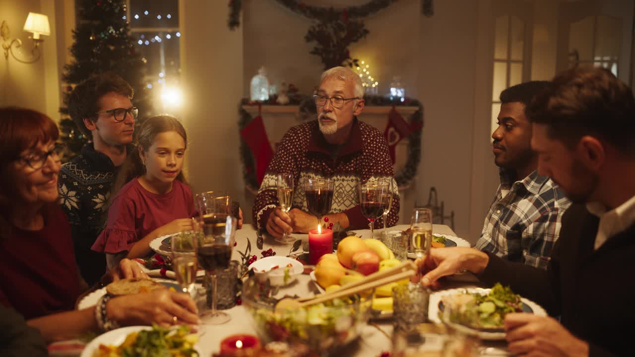 家人、孩子和朋友在下午一起在家吃圣诞晚餐。多元文化家庭抚养孩子，碰杯香槟，用美味的火鸡大餐庆祝节日视频下载