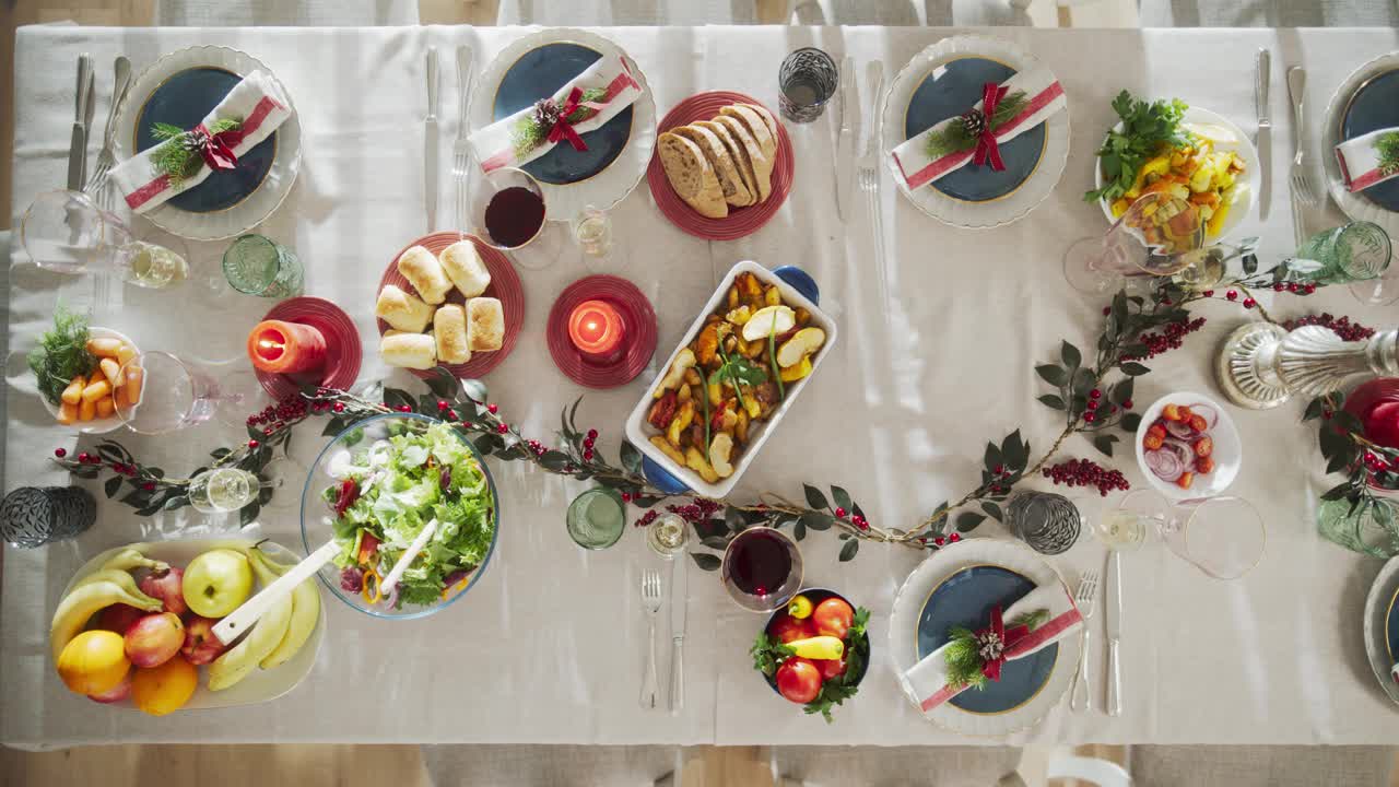 餐厅准备圣诞晚餐。不知名的人上菜，把火鸡烤和其他菜放在餐桌上，装饰蔓越莓灌木和蜡烛。自顶向下镜头视频下载