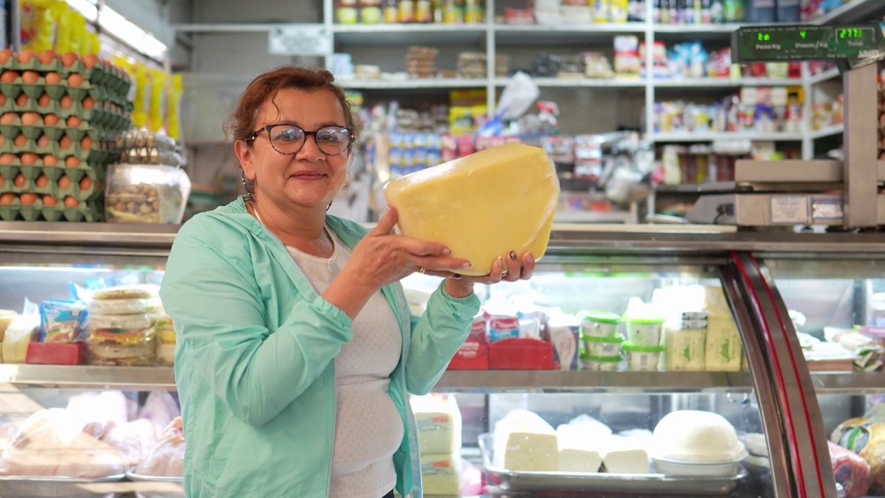 一个成熟的女店员在超市拿着奶酪的肖像视频下载
