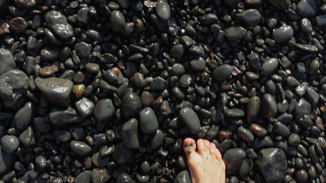 赤脚走在特内里费岛的火山卵石海滩上，普拉亚-德-洛斯-吉奥斯。视频下载