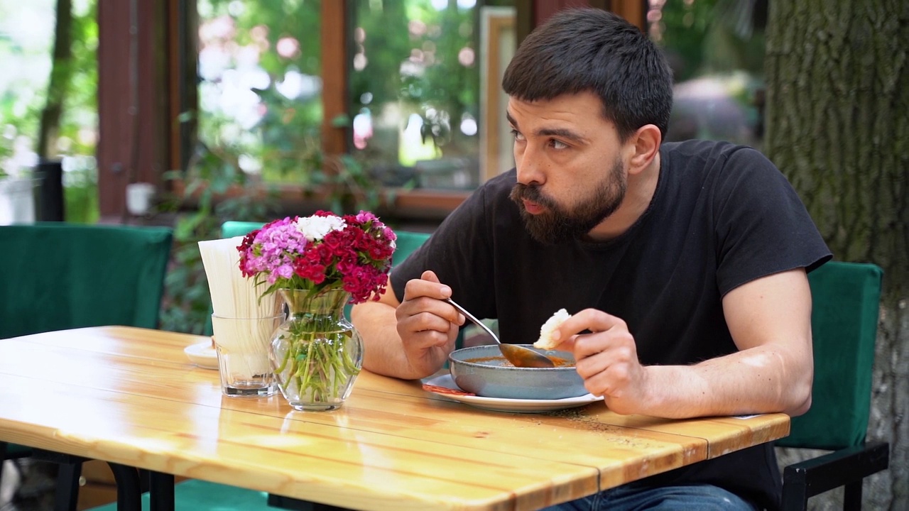 一个男人在餐厅的阳台上喝着美味的汤视频下载